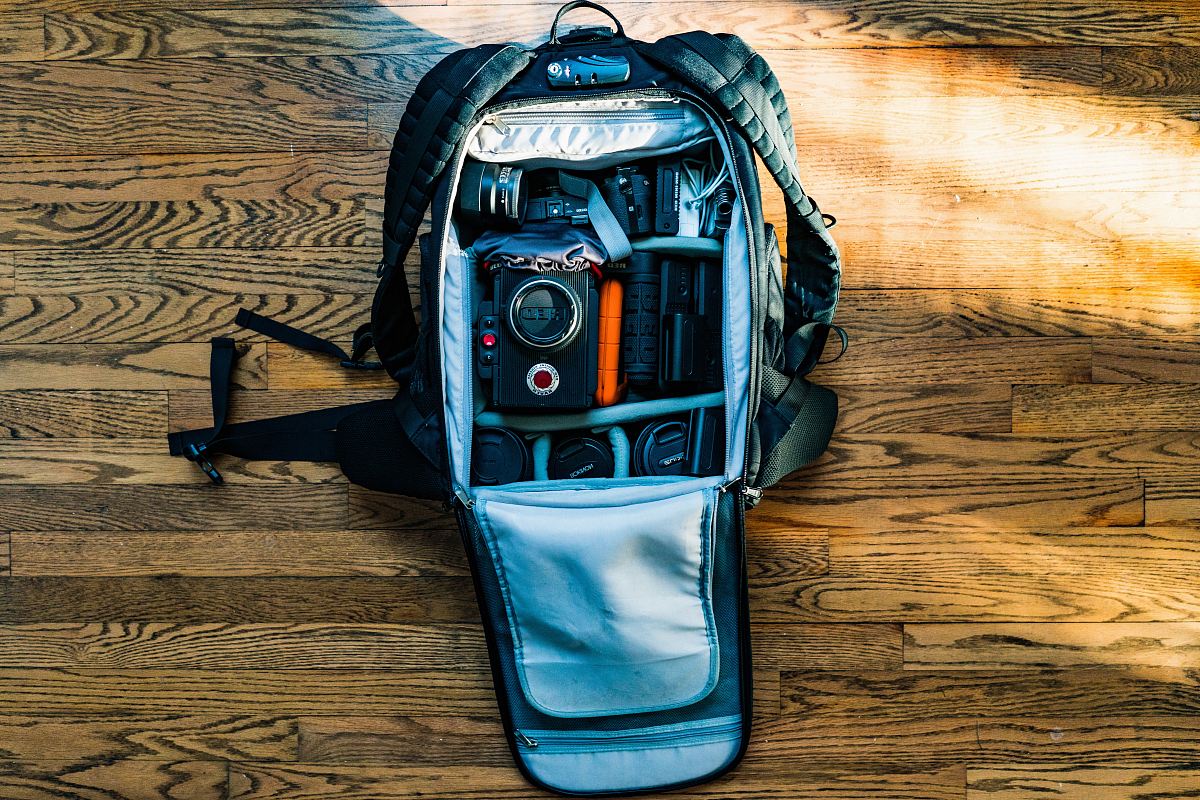 flat-lay photography of DSLR camera in backpack on wood parquet floor